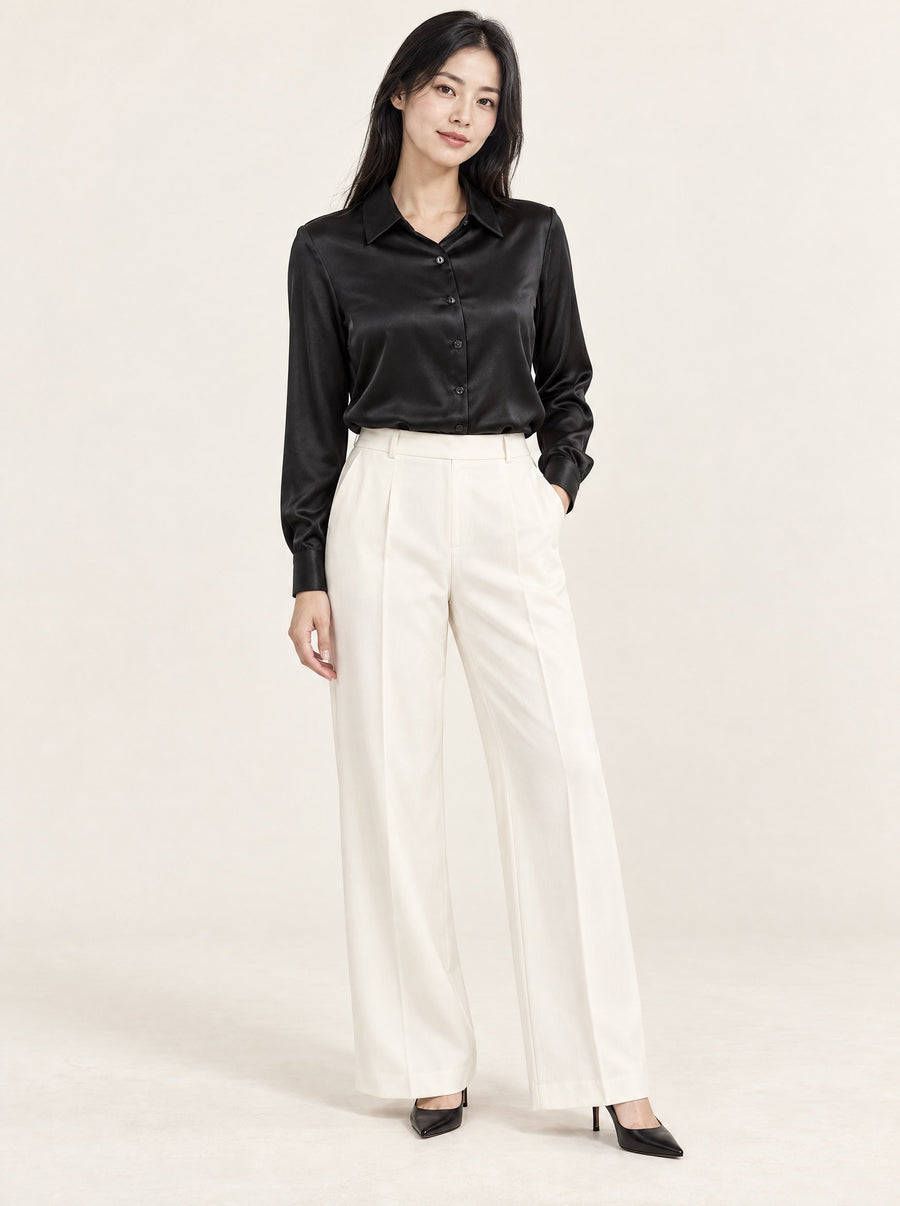 Black silk satin shirt tucked into ivory trousers, in the studio