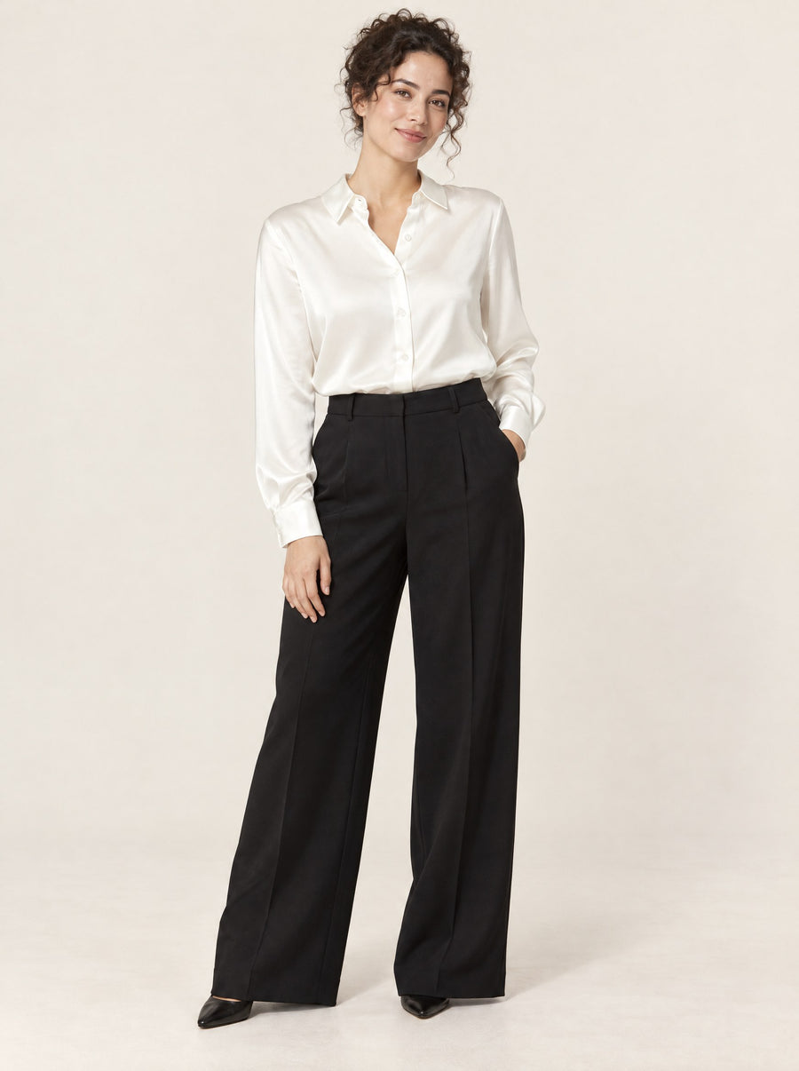 White silk satin shirt tucked into black trousers, in the studio