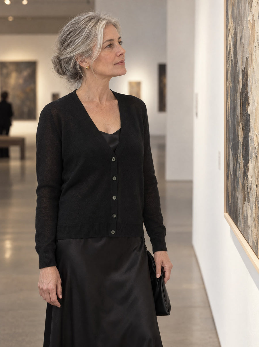 Black cardigan worn over a slip dress at a gallery