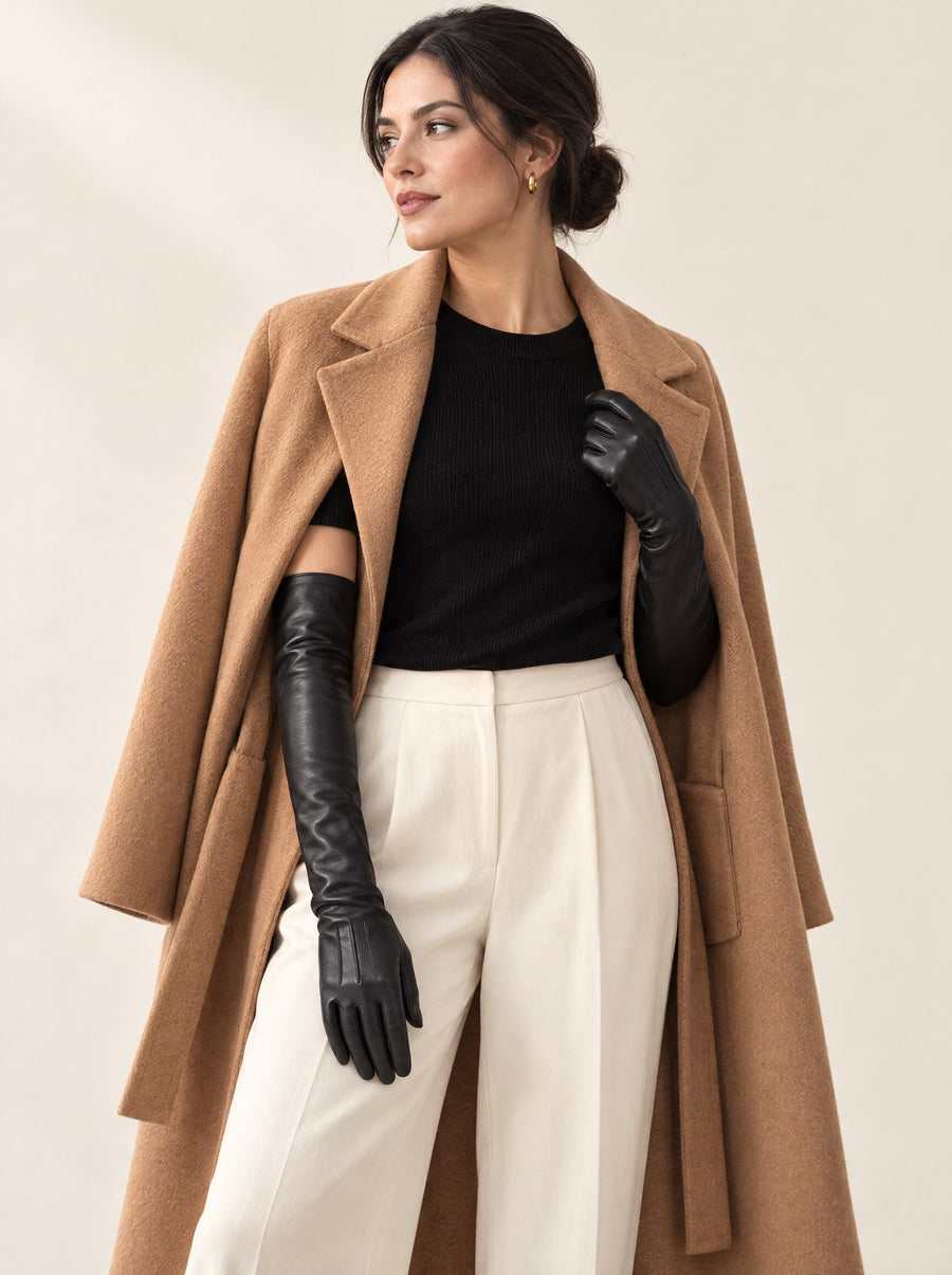Black opera-length leather gloves worn with a camel coat over the shoulders